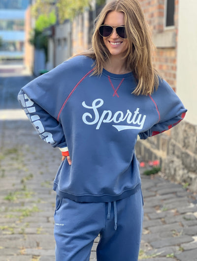 Hammill & Co New Sporty sweat is in a soft brushed fleece fabric in a washed denim blue colour with stripe rib cuffs. Cute printed Sporty print on the front and Word Series down each sleeve in washed white and Retro 1975 print across the back.