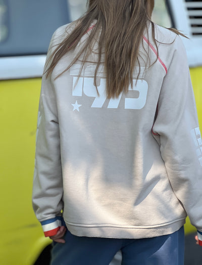 Hammill & Co New Sporty sweat is in a soft brushed fleece fabric in a washed natural colour with stripe rib cuffs. Distressed Red 75 print on the front and Word Series down each sleeve in washed white and Retro 1975 print across the back.