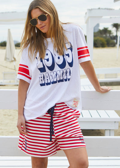 Hammill & Co White slouchy tee with navy 1985 print on the front and red stripes on each sleeve. Our standard over size fit, the same as our logo tees.