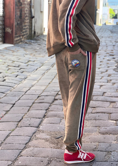 Hammill & Co Sporty velour track pants in soft khaki. Featuring stripe tape down each leg, natural draw cord with elastic waist and woven badge on the back pockets.