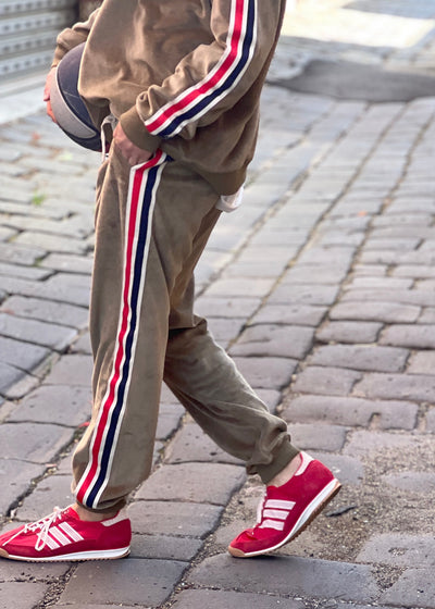 Hammill & Co Sporty velour track pants in soft khaki. Featuring stripe tape down each leg, natural draw cord with elastic waist and woven badge on the back pockets.