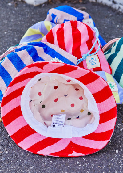 Hammill & Co bold striped bucket hat is pure summer happiness. Made from soft terry towelling in vibrant mauve/lemon stripes, it adds a playful pop to any outfit. 